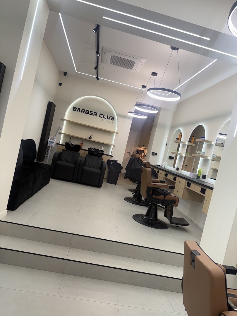 Vue du salon depuis l'entrée : bacs à shampoing, fauteuils et suspensions lumineuses